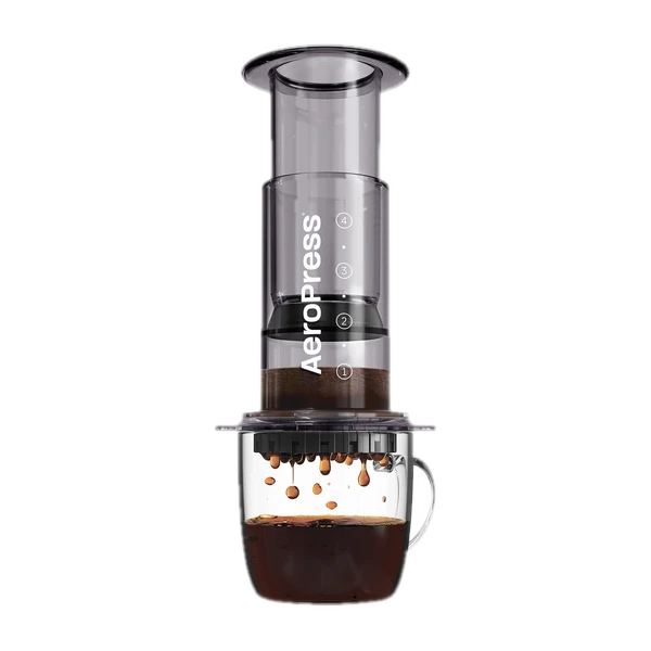 Zdjęcie czarnego zaparzacza AeroPress Clear Black, umieszczonego na szklance z zaparzaną kawą. Krople kawy spadają do kubka, ukazując proces parzenia metodą AeroPress, z przezroczystym czarnym korpusem urządzenia.