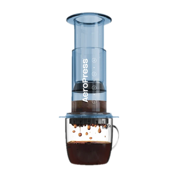 Zdjęcie niebieskiego zaparzacza AeroPress Clear Blue, umieszczonego na szklance z zaparzaną kawą. Krople kawy spadają do kubka, ukazując proces parzenia metodą AeroPress, z przezroczystym niebieskim korpusem urządzenia.